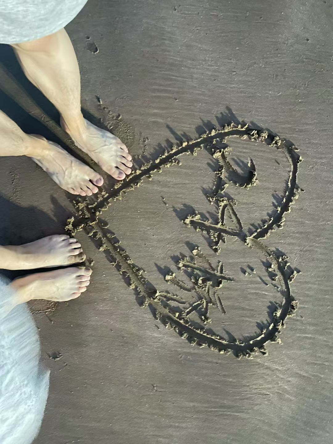 两个人在沙滩画下心形